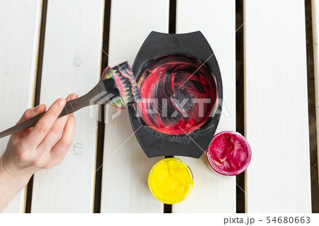 Coloring and hair stylist concept - hands of hairdresser is mixing a colour for hair, top view Coloring and hair stylist concept - hands of hairdresser is mixing a colour for hair, top view 54680663