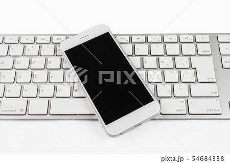 スマホ スマートフォン とpcキーボード 白バック シンプルイメージの写真素材
