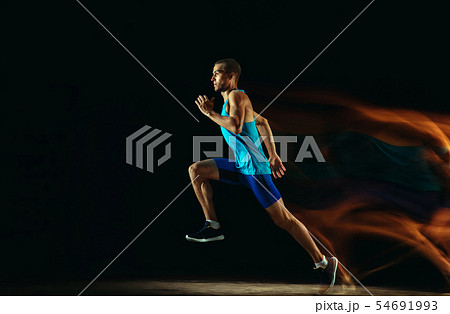 Professional male runner training isolated on black studio background in mixed light 54691993