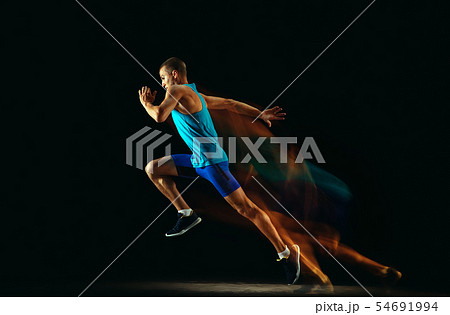 Professional male runner training isolated on black studio background in mixed light 54691994