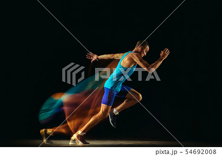 Professional male runner training isolated on black studio background in mixed light Professional male runner training isolated on black studio background in mixed light 54692008