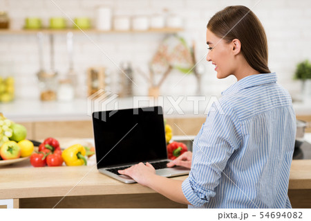 Woman searching recipes online on laptop with blank screen Woman searching recipes online on laptop with blank screen 54694082