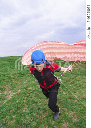Landed young male skydiver paraglider extinguishes Landed young male skydiver paraglider extinguishes 54696061