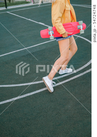 young girl in a yellow jacket and pink skateboard young girl in a yellow jacket and pink skateboard 54724748