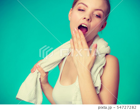 Bored sleepy woman yawning while holding towel 54727282