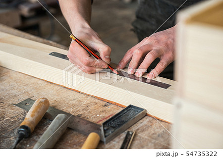 The worker makes measurements of a wooden board The worker makes measurements of a wooden board 54735322