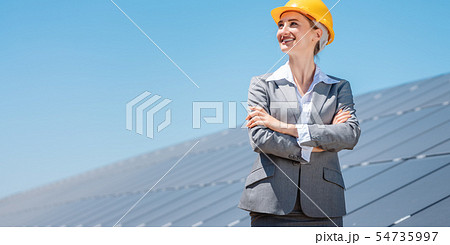 Woman investor in clean energy standing in front of solar panels Woman investor in clean energy standing in front of solar panels 54735997