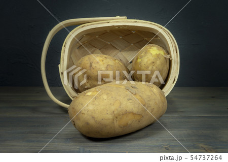 Potatoes spilling out of tipped wicker basket 54737264
