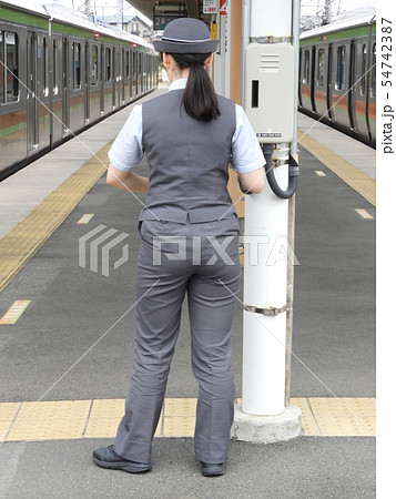 ホームに一人ぽつんと立つ女性車掌さんの後ろ姿の写真素材