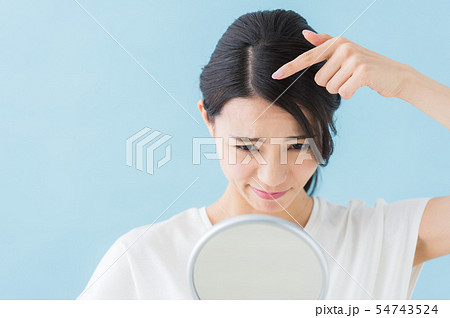 ヘアチェックする女性 青背景 の写真素材