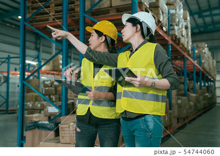 colleagues point finger at shelf in storehouse. 54744060