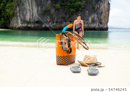 Beach bag and travel accessories with woman in blur background on vacation. Beach bag and travel accessories with woman in blur background on vacation. 54746245