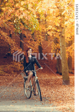 Red haired girl riding on bike in autumnal park 54753045