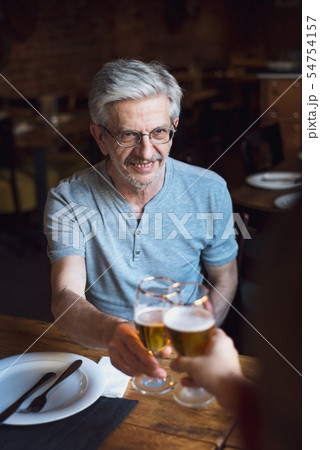Senior man toasting with a beer in a bar Senior man toasting with a beer in a bar 54754157