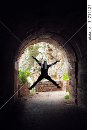 Man jumping in a dark tunnel Man jumping in a dark tunnel 54755122