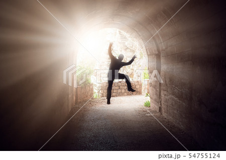 Man jumping in a dark tunnel Man jumping in a dark tunnel 54755124