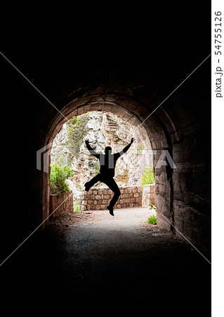 Man jumping in a dark tunnel Man jumping in a dark tunnel 54755126