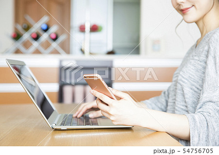 女性 若い女性 主婦 パソコン ノートパソコン スマホ リビング ライフスタイルの写真素材