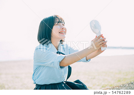 手持ち扇風機を使う女子高生 54762289