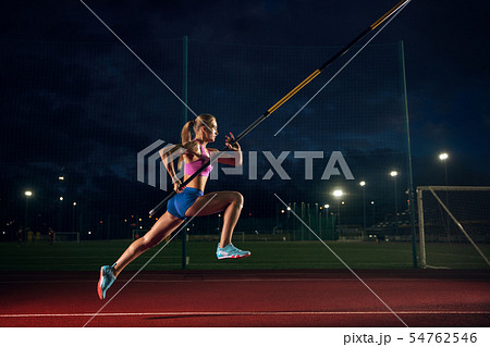Female pole vaulter training at the stadium in the evening 54762546