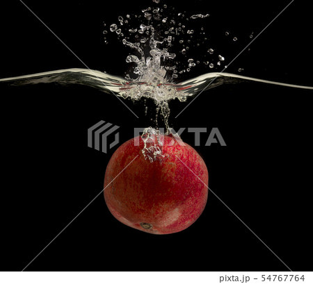 Ripe red pomegranate falling deeply under water with bubbles Ripe red pomegranate falling deeply under water with bubbles 54767764