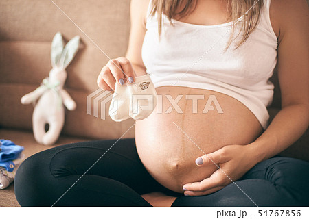 Front view of future mother keeping little socks of baby Front view of future mother keeping little socks of baby 54767856