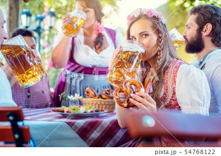 Woman in Tracht looking into camera while drinking a mass of beer Woman in Tracht looking into camera while drinking a mass of beer 54768122
