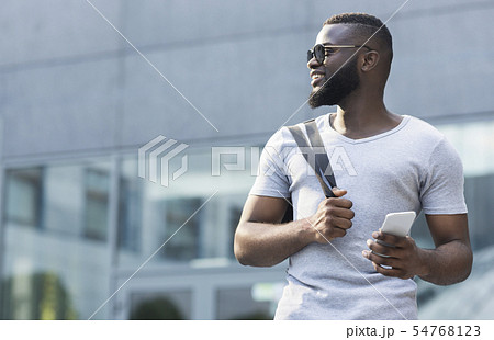 Handsome african american guy with cellphone looking away Handsome african american guy with cellphone looking away 54768123