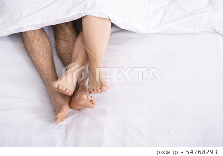Loving couple legs lying on bed under blanket 54768293