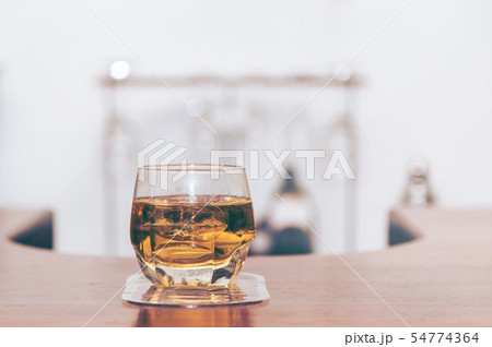 Glass of whiskey with ice cubes served on wooden Glass of whiskey with ice cubes served on wooden 54774364