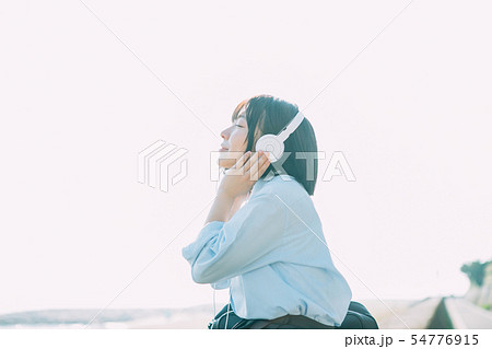 海の近くで音楽を聴く女子高生 54776915