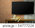 Cat sitting on wood table with Tv on brick wall 54777226