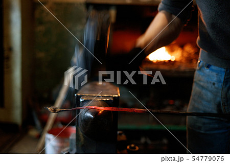 Blacksmith forging red-hot metal with hammer. 54779076