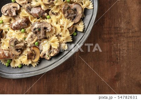 Mushroom and cheese pasta. Farfalle with cremini and green peas 54782631