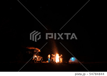 Happy Friends having a rest together around campfire Happy Friends having a rest together around campfire 54784844