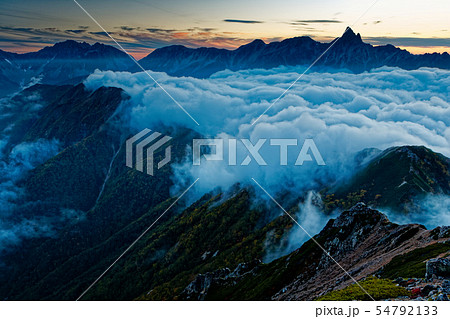 大天井岳から見る滝雲流れる東鎌尾根と夕暮れの槍ヶ岳の写真素材