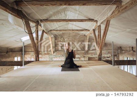 Young woman exercises yoga on an abandoned construction site 54793292