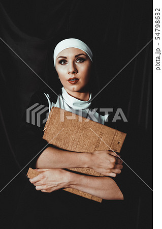 Beautiful young nun in religion black suit holds Bible. Religion concept Beautiful young nun in religion black suit holds Bible. Religion concept 54798632