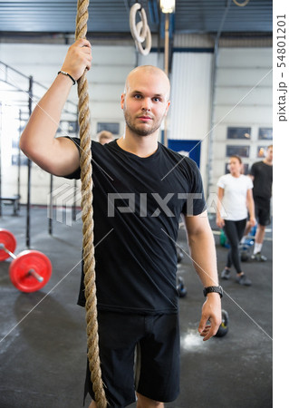 Confident Male Athlete Holding Gym Rope In Health Club 54801201