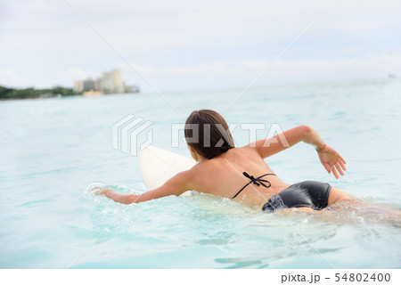 Surfer girl surfing paddeling on surfboard 54802400