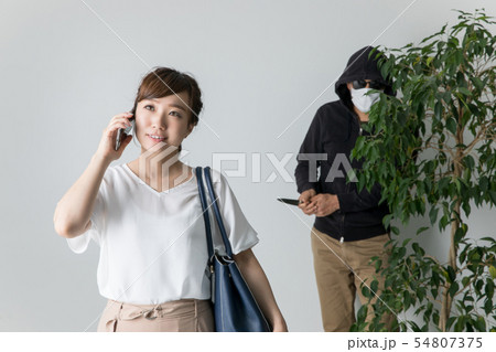 スマホで犯罪者に気づかない女性 スマホで犯罪者に気づかない女性 54807375