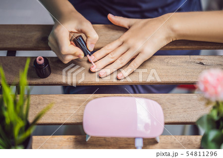 Young woman makes manicure with gel polish and UV lamp in pink shades 54811296