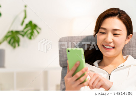 部屋でスマホを見る女性　 54814506