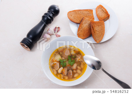 Bean soup in white plate with metal spoon, several 54816252