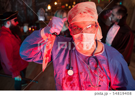 Attractive young man in a doctor costume holding a knife at halloween party Attractive young man in a doctor costume holding a knife at halloween party 54819408