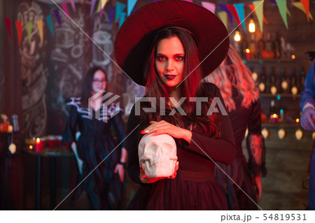 Young beautiful witch doing dark magic on a human skull for halloween celebration Young beautiful witch doing dark magic on a human skull for halloween celebration 54819531