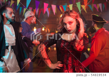 Beautiful woman dressed in a black dress for halloween celebration with a scary makeup 54819534