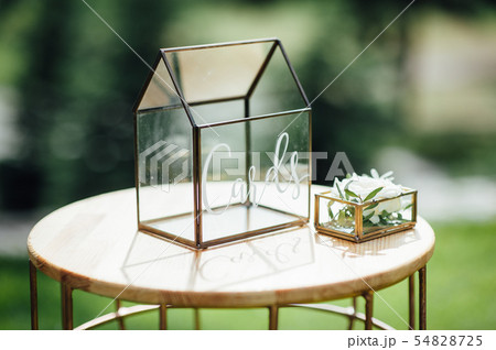 Wedding table decoration. Beautiful bouquet of flowers in vase on the table, glasses and gift boxes. 54828725