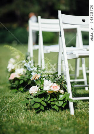 Outgoing wedding ceremony. Decor Studio. white wooden chairs on a green lawn. 54828726