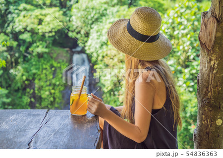 Closeup portrait image of a beautiful woman drinking ice tea with feeling happy in green nature and 54836363